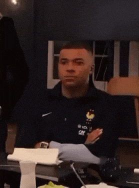 a man is sitting at a table wearing a black nike jacket with a rooster on it