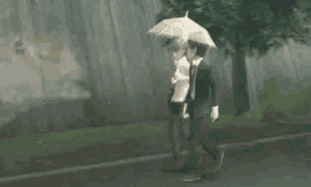 a man and a woman are walking down a street in the rain holding an umbrella .