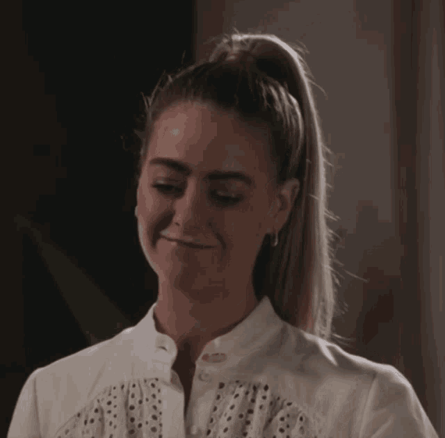 a woman with her hair in a ponytail looks down
