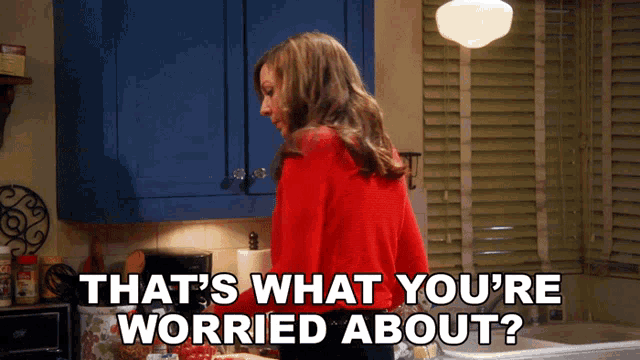 a woman in a red sweater is standing in a kitchen with the words that 's what you 're worried about
