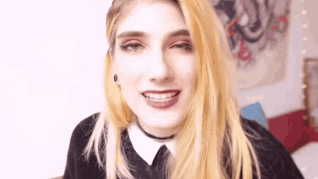 a close up of a woman 's face with blonde hair and a choker around her neck .