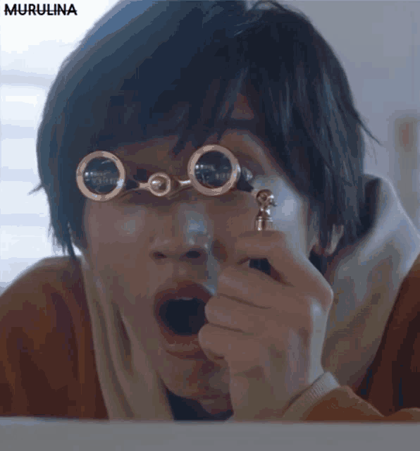 a close up of a person wearing a pair of glasses with the word murulina on the bottom left