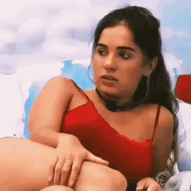 a woman in a red top is sitting on a couch with her legs crossed .