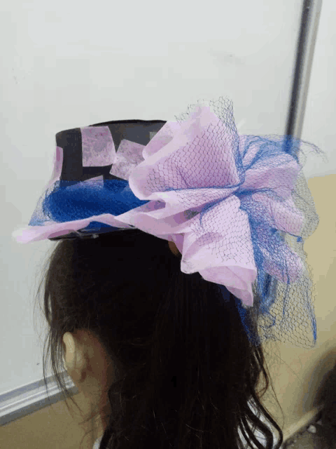 a woman wearing a hat with a blue and pink bow