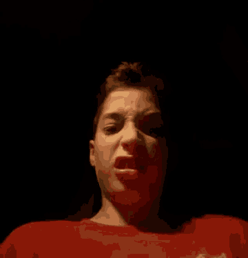 a young boy in a red shirt is making a funny face .