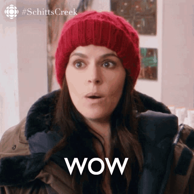 a woman wearing a red hat and a jacket with the word wow on her face