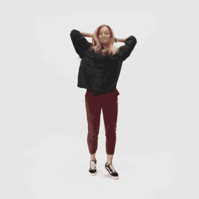 a woman in a black sweatshirt and maroon pants is dancing