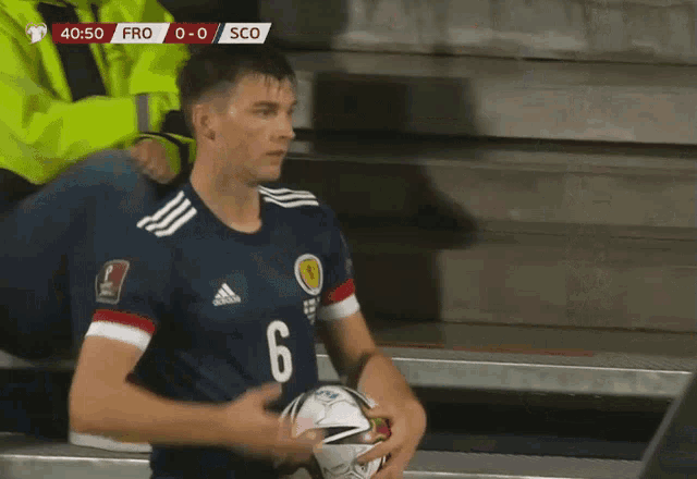 a soccer player with the number 6 on his jersey holds a ball