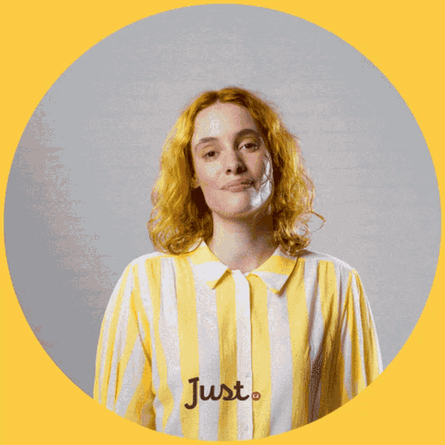 a woman in a yellow and white striped shirt is holding a yellow heart in front of her face and the word just is on the shirt