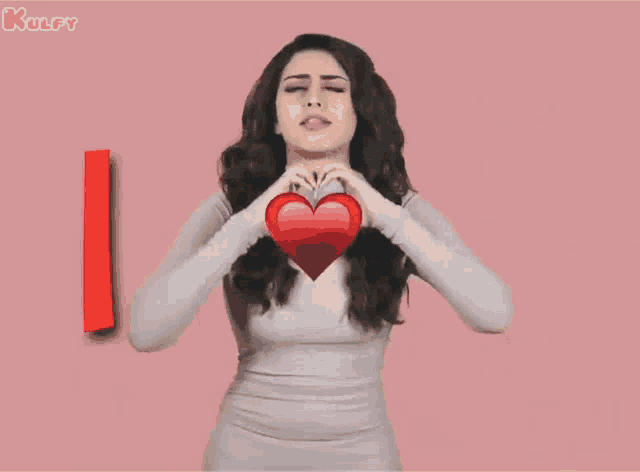 a woman in a white dress is holding a red heart and says i love u