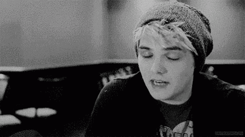 a black and white photo of a man wearing a beanie and a black shirt .