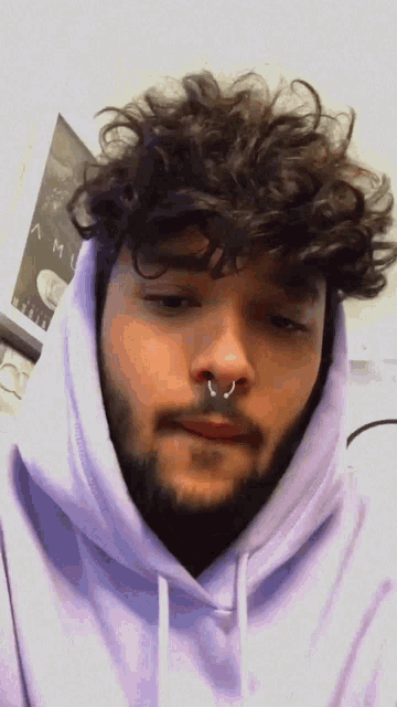 a man wearing a purple hoodie with a nose ring