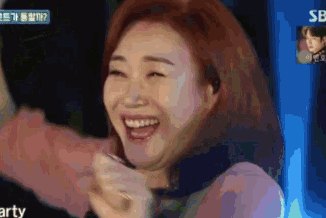 a woman is laughing in front of a blue screen that says sb