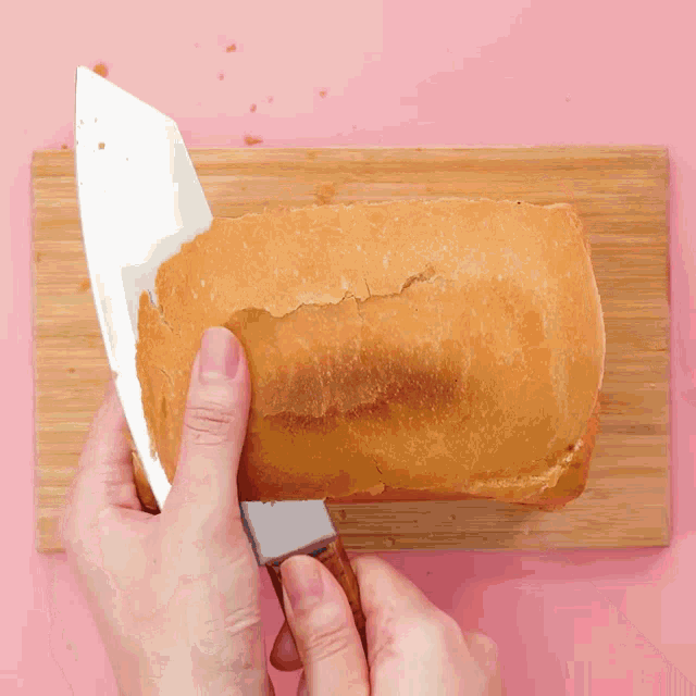someone is cutting a loaf of bread with a knife