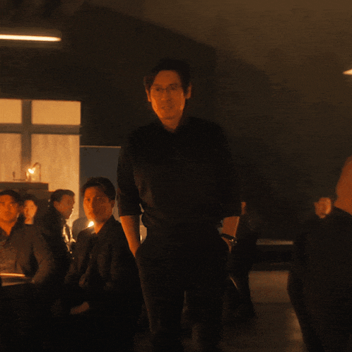 a man in a black shirt stands in a dark room