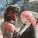 a man and a woman with pink hair are standing next to each other .