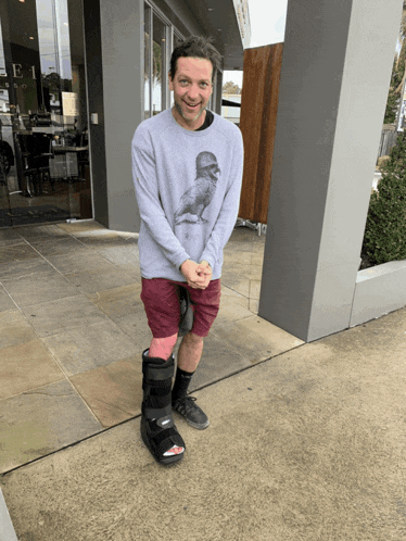 a man wearing a sweater with a bird on it is standing on a sidewalk