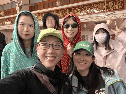 a woman wearing a green hat that says positive poses for a picture
