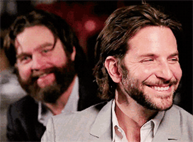a man with a beard is smiling while another man with a beard is laughing
