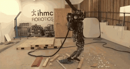 a robot is standing in a room with ihmc robotics written on the wall behind it