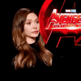 a woman stands in front of a sign that says avengers infinity war