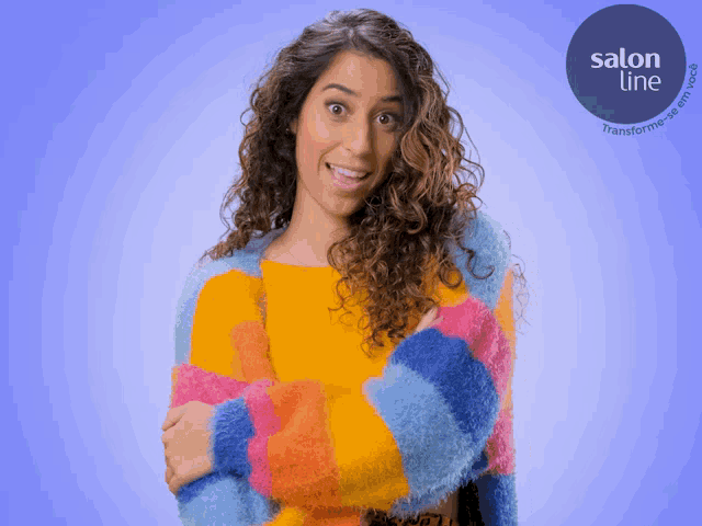 a woman with curly hair is wearing a colorful sweater with salon line written on the bottom