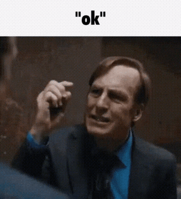 a man in a suit and blue shirt is making a funny face and saying okay .