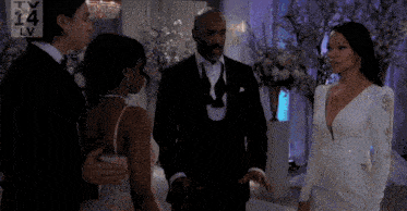 a man in a tuxedo stands next to a woman in a wedding dress