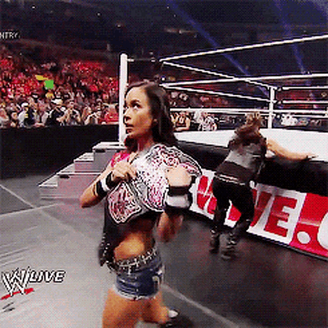 a woman in a wrestling ring with the words w live on the bottom left