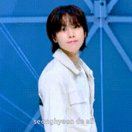 a young man with short hair is standing in front of a blue wall .