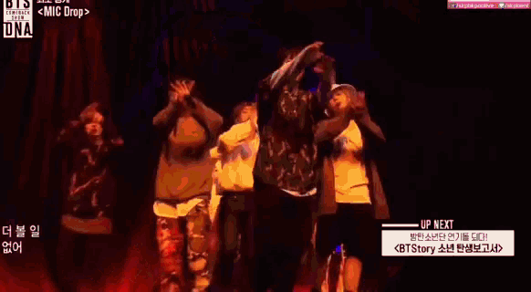 a group of people are dancing on a stage and one of them is wearing a bucket hat