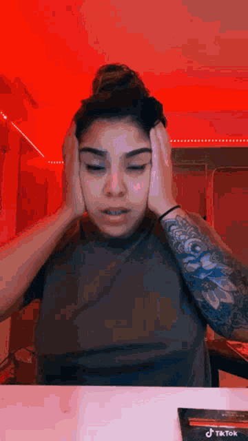 a woman covering her ears with her hands in front of a red light .