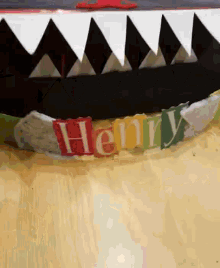 henry is written on a colorful banner with shark teeth on it