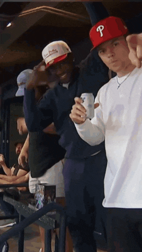 a man wearing a red hat with the letter p on it holds a can of beer