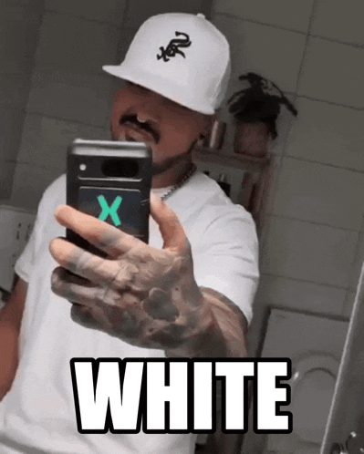 a man in a white hat takes a selfie in front of a mirror with the word white below him