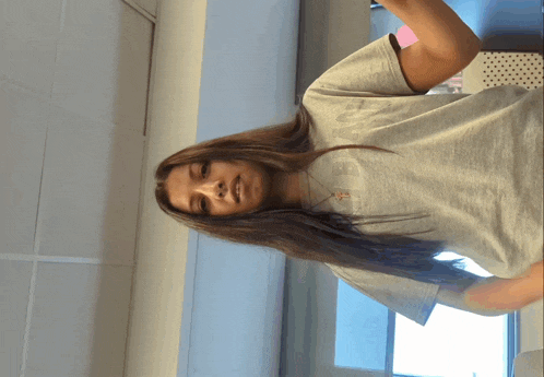a girl with long hair is wearing a grey shirt with the word champion on the front