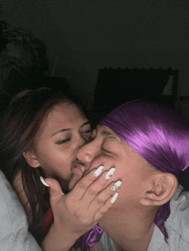 a man wearing a purple head scarf kisses a woman