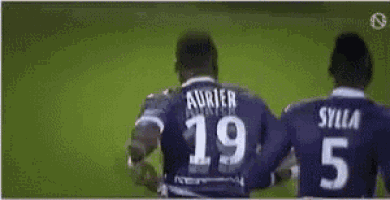 two soccer players wearing purple jerseys with the number 19 and 5 on the back