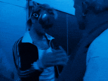 a man wearing oakley goggles talks to another man in a blue room