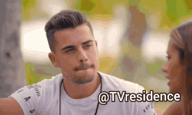 a man and a woman are looking at each other and the man is wearing a white t-shirt with the word tvresidence on it