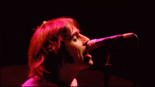 a man is singing into a microphone in a dark room