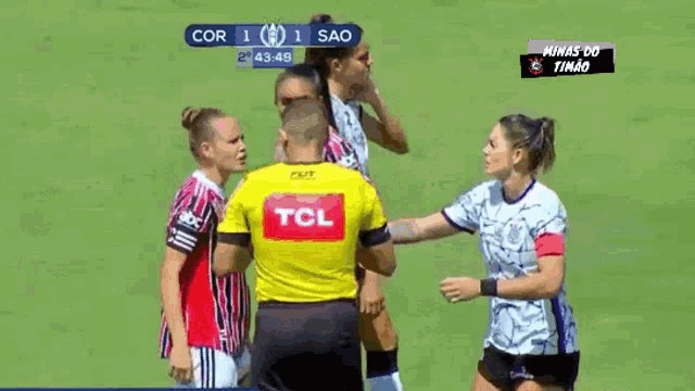 a group of female soccer players standing around a referee wearing a yellow tcl jersey