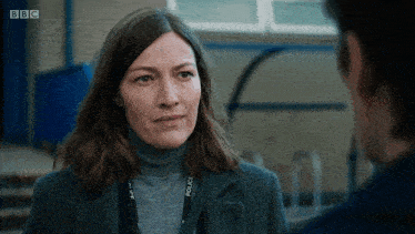 a woman with a police lanyard around her neck talks to another man