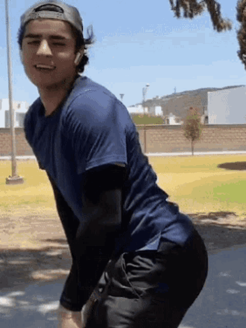 a young man wearing a baseball cap and a blue shirt is squatting down