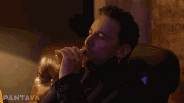a man sits in a chair smoking a cigarette with pantaya written in the corner