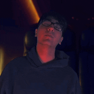 a man wearing glasses and a black hoodie looks up into the sky