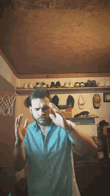 a man in a blue shirt is standing in a room with a basketball net in the background