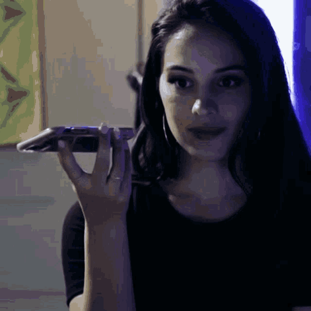 a woman in a black shirt is holding a cell phone to her ear