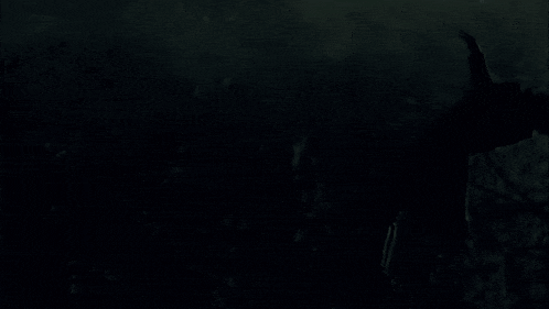 a silhouette of a person standing in the dark with their arm outstretched
