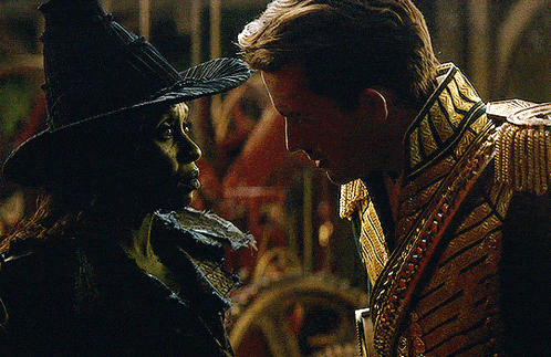 a man and a woman are looking at each other and the woman is wearing a witch costume